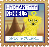 A yellow dog with a yellow diamond above their head looks at the camera against a background of a forest. The text reads 'Hydrargyry Kennelz' at the top and 'Spectacular...!' at the bottom. The stamp is orange, with blue text.